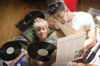 Pár sa pozerá na vinylové platne, keď leží na podlahe