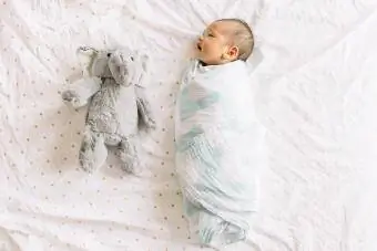طفل مقمط في السرير مع فيل محشو