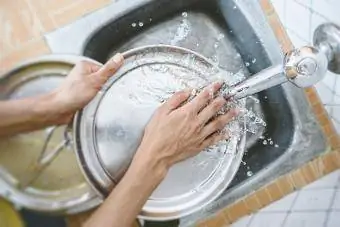 Kadın mutfak lavabosunda bulaşık yıkıyor