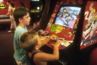 2 anak laki-laki kecil bermain video game Street Smart di video arcade di trotoar