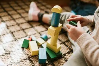 बच्चा रंगीन लकड़ी के ब्लॉक और स्टैकिंग आकार बना रहा है