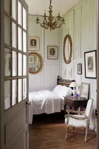 लकड़ी की दीवार पैनलिंग और फ्रेंच प्राचीन वस्तुओं के साथ आकर्षक बेडरूम