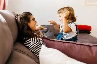 Glückliche Mutter und Tochter unterh alten sich, während sie sich zu Hause auf dem Sofa entspannen