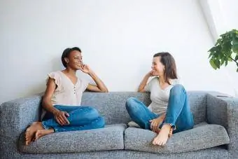 Dvě uvolněné ženy sedí na gauči doma mluví
