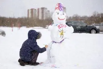 Pojke målar en snögubbe på en vinterdag