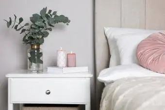 Vaza s čudovitimi vejami evkaliptusa, knjiga in sveče na nočni omarici v spalnici