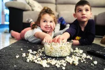 Geschwister schauen sich einen Heimfilm an, während sie Popcorn essen