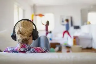 Moeder draagt een koptelefoon terwijl haar kinderen aan het spelen zijn