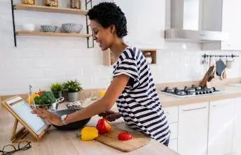 wanita menggunakan tablet memasak di dapur di rumah