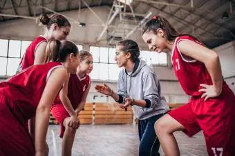 Treneris stāv ar basketbola komandu