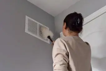 Babaeng naglilinis ng return air vent gamit ang duster