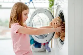 Petite fille mettant un jouet dans une machine à laver