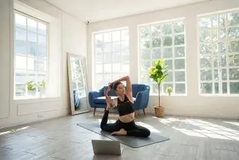 Jovem praticando iyengar yoga em casa, na sala de estar
