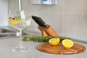 Gin og tonic med sitron og rosmarin i krystallglass på kjøkkenbordet