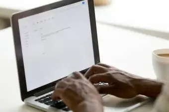 Afroamerikkalainen liikemies kirjoittaa sähköpostia kannettavalla tietokoneella