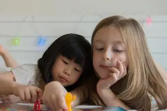 Meninas jogando um jogo de mesa em uma cama