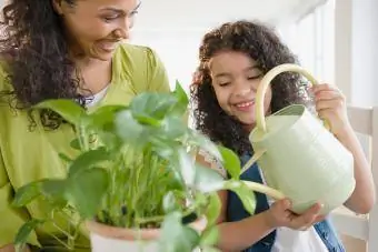 Майка и дъщеря поливат растения заедно