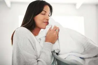 giovane donna che sente l'odore della biancheria pulita a casa