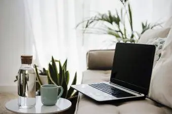 Laptop por almofadas no sofá em casa