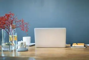 ლეპტოპი დღიურებით და დეკორაციებით მაგიდაზე სახლის ოფისის ცისფერ კედელზე