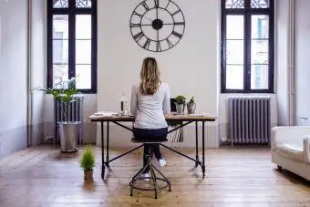 Vue arrière d'une femme assise au bureau à la maison