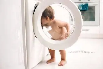 bayi berdiri berhampiran mesin basuh