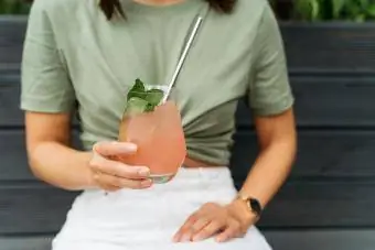 Ritratto di una donna con in mano un cocktail paloma seduta su una panchina