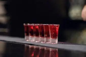 Il barista versa alcol rosso negli shot sul bancone