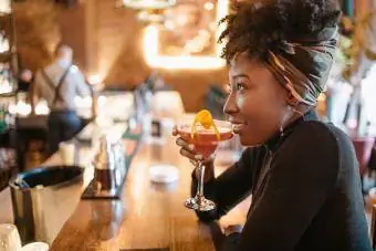 Молодая женщина занимается космополитизмом, сидя в баре
