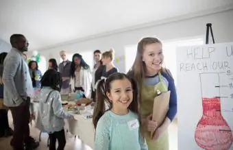 meninas em pé na venda de bolos para arrecadação de fundos