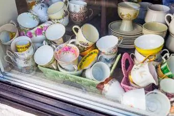 Une variété de vieilles tasses, soucoupes, pichets et autres articles de vaisselle à vendre dans une vitrine de magasin d'occasion