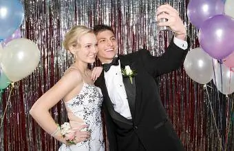 Adolescente y niña tomando una fotografía en el baile de graduación