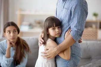 Esikoululainen tytär halaa isäänsä surullisesti