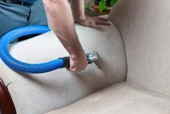 Mann reinigt Sofa mit Dampfreinigung zu Hause