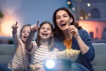 Moeder en dochters eten popcorn op filmavond uit de jaren 80