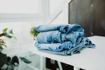 Foldet bunke jeans på hvidt træbord derhjemme