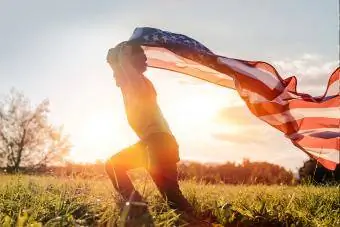 Gün batımında Amerikan bayrağıyla koşan küçük çocuk