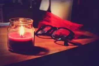 شمعة مضاءة في الجرة والنظارات على الطاولة