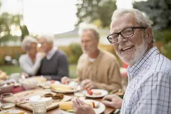 Glimlaggende senior man geniet tuinpartytjie