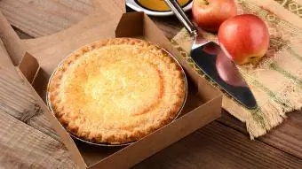 Φρεσκοψημένη μηλόπιτα σε κουτί σε ξύλινο τραπέζι