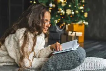 Mujer leyendo un libro junto al árbol de Navidad