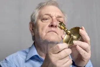 Senior man undersöker antik ljusstake