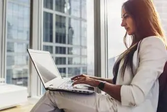 Vista laterale di un'imprenditrice fiduciosa che utilizza un computer portatile seduto nel moderno centro business