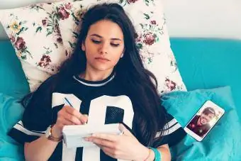 Genç kız yatakta günlüğüne yazıyor