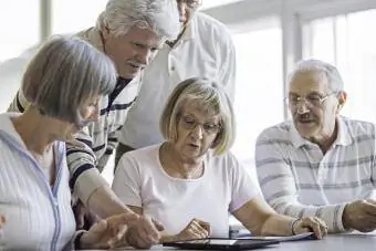 Groupe de personnes âgées regardant une tablette numérique en classe