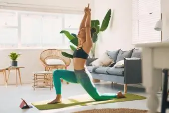 Ung kvinna som utövar yoga hemma