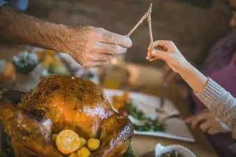 Hindi nakikilalang lalaki at bata na humihila ng wishbone sa Thanksgiving dinner