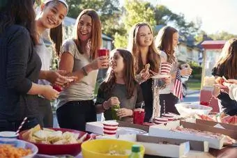Mädchen stehen und unterh alten sich an einem Essenstisch für eine Schulparty
