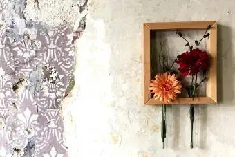क्षतिग्रस्त दीवार पर फ्रेम में फूल