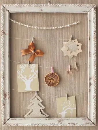 Bröllopsdesignerdekor i form av en ram med ringar, pärlor, en rosett av satinband, torkad apelsinskiva och utklippta bilder
